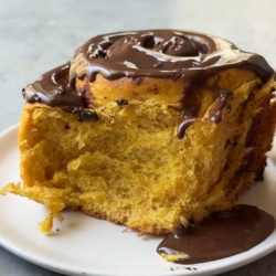 one serving of chocolate pumpkin cinnamon roll on white plate.