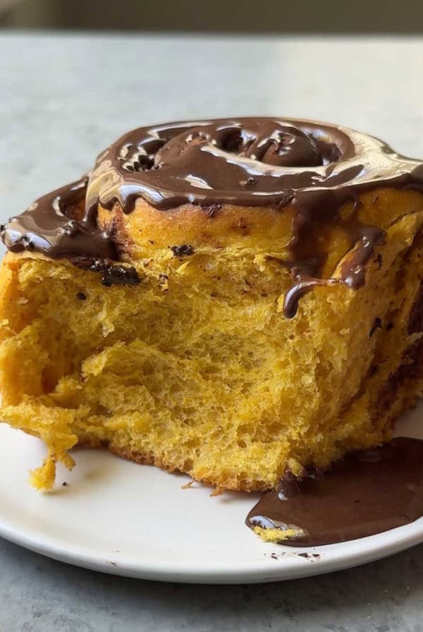 one serving of chocolate pumpkin cinnamon roll on white plate.
