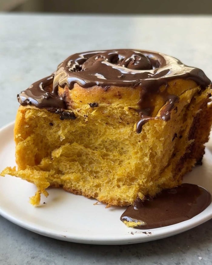 one serving of chocolate pumpkin cinnamon roll on white plate.