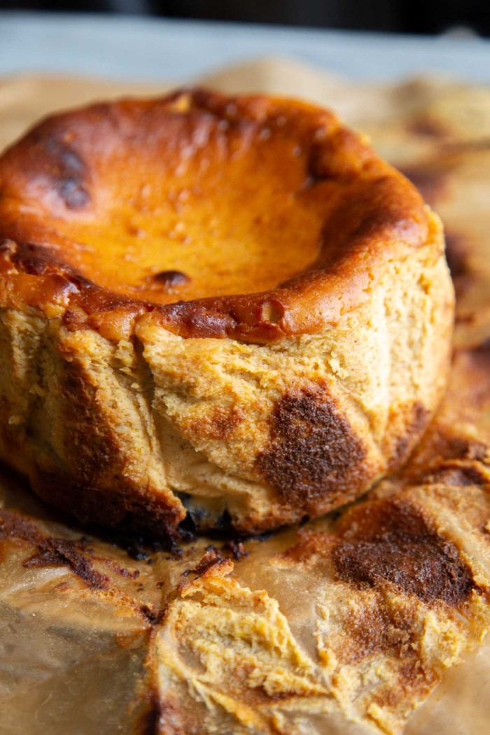 quarter view Basque style pumpkin cheesecake on parchment paper.