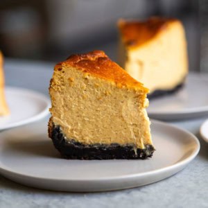 slice of oreo crust pumpkin Basque cheesecake on grey plate.