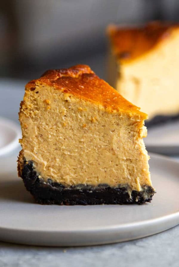 slice of oreo crust pumpkin Basque cheesecake on grey plate.